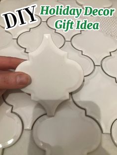 a hand is holding a white tile with the words diy holiday decor gift idea