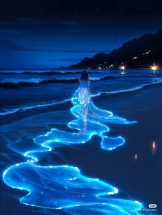 a woman is walking on the beach at night with blue lights all over her body