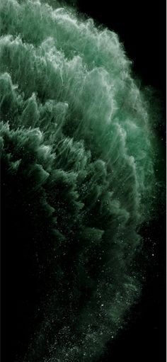 the water is green and white as it splashes into the air on a black background