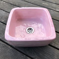 a pink sink sitting on top of a wooden table