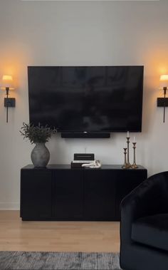 a flat screen tv mounted on the wall above a black cabinet in a living room