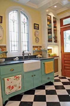 a kitchen with black and white checkered flooring, blue cabinets and an old fashioned sink