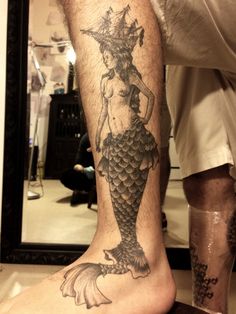 a man with a mermaid tattoo on his leg