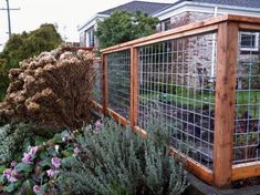 a fenced in garden area with flowers and plants growing on the side of it