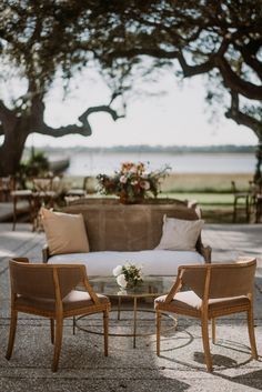 two chairs and a table with flowers on it in the middle of an outdoor area