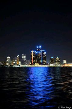 the city skyline is lit up at night from across the water with bright lights on it