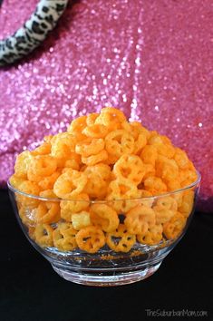 a bowl filled with cheetos sitting on top of a table next to a pink sequin wall