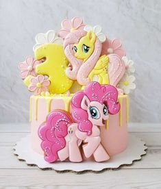 a pink and yellow cake decorated with little ponys