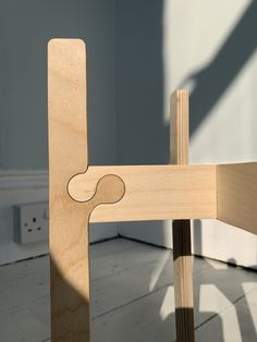 a wooden chair sitting on top of a hard wood floor next to a white wall