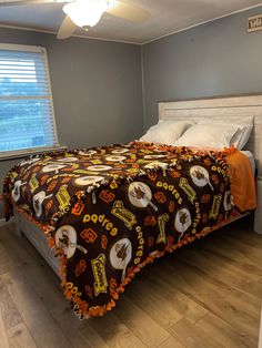 a bed in a bedroom with a brown and orange comforter on top of it