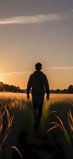 a person walking through a field at sunset