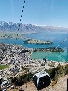 a cable car going up the side of a mountain with a lake and mountains in the background