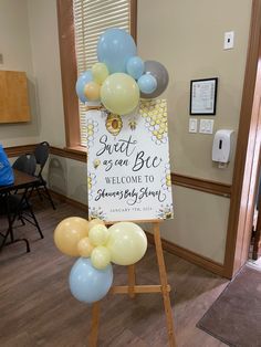 a welcome sign with balloons in the shape of bees and honeybees on it