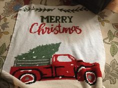 a red truck carrying a christmas tree on it's back with the words merry christmas