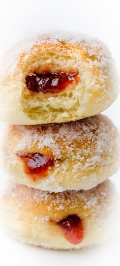 three doughnuts stacked on top of each other covered in powdered sugar and jelly