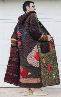 a man standing in front of a garage door wearing a multicolored knitted coat