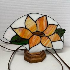 a stained glass flower lamp on a wooden base with a cord in front of it