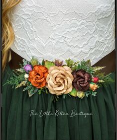 a woman wearing a green dress with flowers on the waist and in front of her is a white lace top