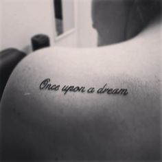 a person with a tattoo that says once upon a dream on their back shoulder and arm