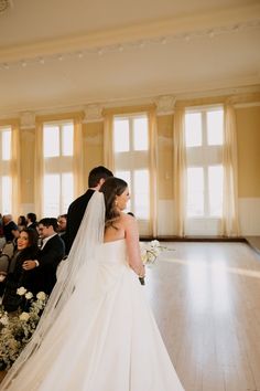 a bride and groom standing in front of an audience at a wedding ceremony with their backs to the camera