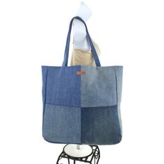 a denim tote bag is on display with a white mannequin behind it