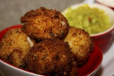 some fried food is in a red bowl and on the table are guacamole