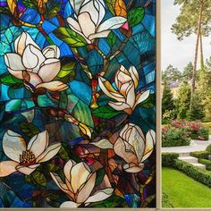 a stained glass window with white flowers in the center and green grass on the other side