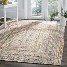 a rug that is on the floor in front of a chair and table with a potted plant