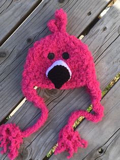 a pink crocheted animal hat sitting on top of a wooden bench