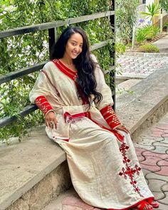 a woman is sitting on the steps wearing a white dress with red trimmings