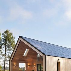 a small house with a pitched roof and solar panels on the roof is surrounded by greenery