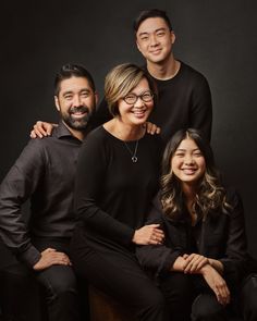 a family posing for a photo with their arms around each other in front of a black background