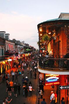 a crowded street with people walking around and buildings in the background at dusk or dawn