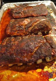 two steaks are sitting on top of some tin foil covered in sauce and seasonings