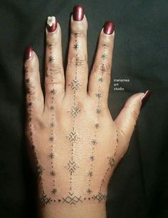 a woman's hand with tattoos on her fingers and the middle finger is shown