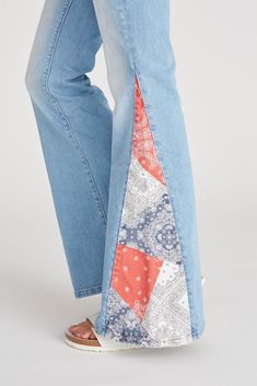 a woman's legs wearing blue jeans with an orange and white patchwork design