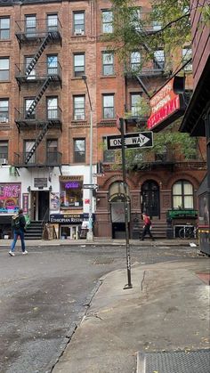 people are walking down the street in front of some tall buildings with fire escapes on them