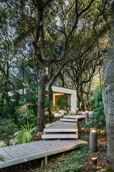 a wooden deck in the middle of a forest with steps leading up to a house