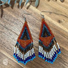 a pair of beaded earrings sitting on top of a wooden table