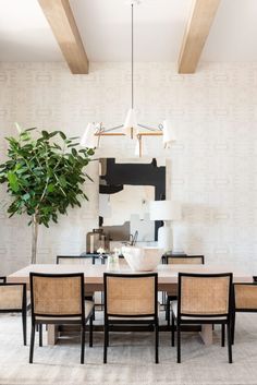 a dining room table with chairs and a potted plant in the center on top of it