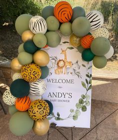 a welcome sign surrounded by balloons in the shape of animals and giraffes