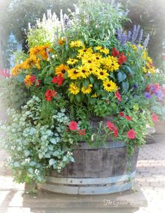 a wooden barrel filled with lots of different colored flowers