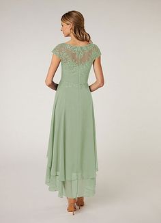 a woman wearing a green dress with lace on the top and sleeves, back view