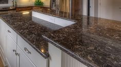 a large kitchen with marble counter tops and white cabinetry, along with stainless steel appliances