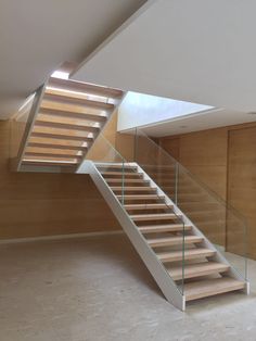 a stair case with glass railing and wooden handrail