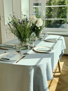 the table is set with place settings and flowers in glass vases on each side