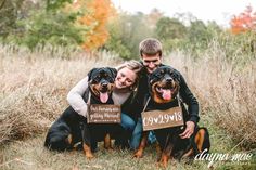 a man and woman holding two dogs in front of them with signs on their heads