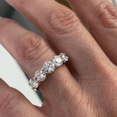 a woman's hand with a three stone diamond ring on her left and right hand