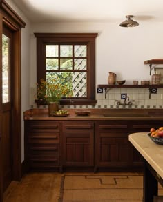 a bowl of fruit is sitting on the counter in this kitchen with wood cabinets and tile backsplash