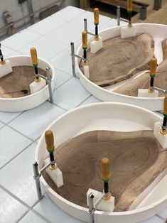 three white bowls with wooden handles on top of a table